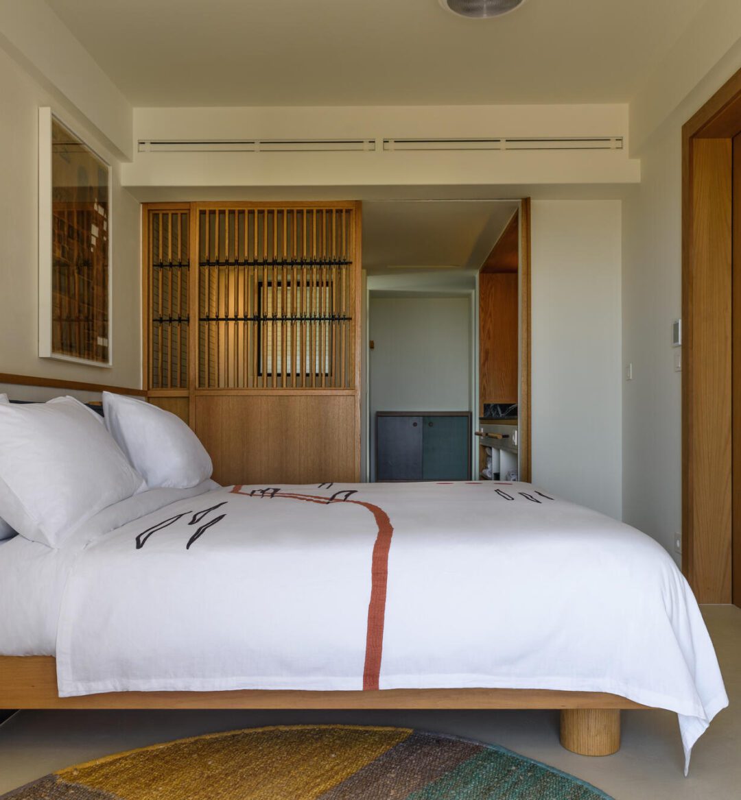 A cozy bed neatly made in a softly lit bedroom, with warm colors and simple decor.