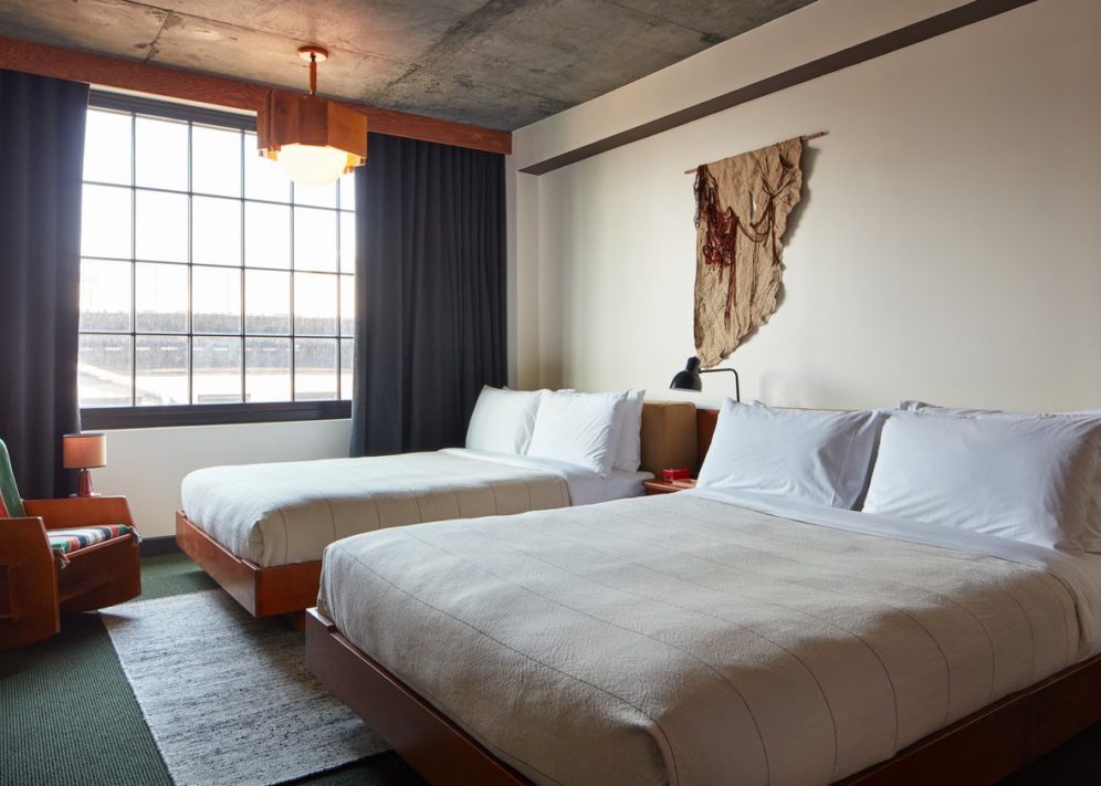 A room with modern styling and hanging light fixture suspended from a concrete ceiling