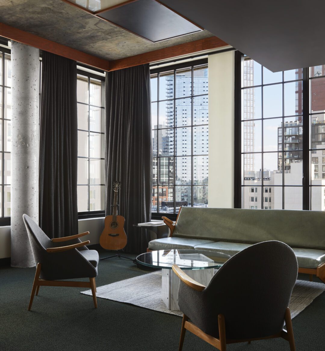 A living area featuring a modern concrete column and corner windows providing city views from multiple angles