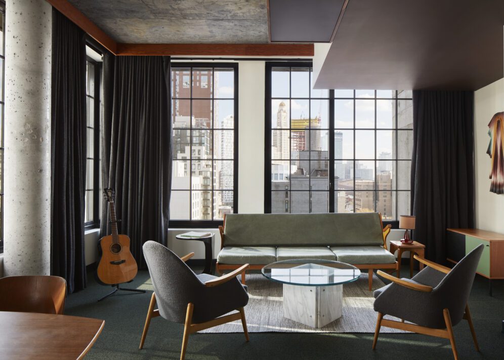 Spacious living space with multiple chairs and a sofa with windows on multiple walls providing sweeping city views