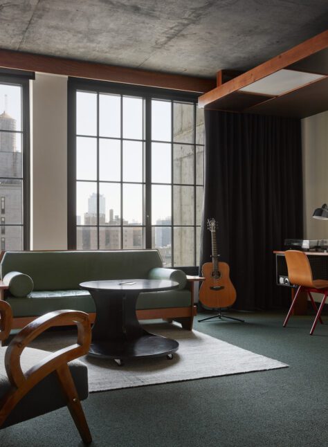 A high-floored room with a desk for work, multiple seating options and natural light