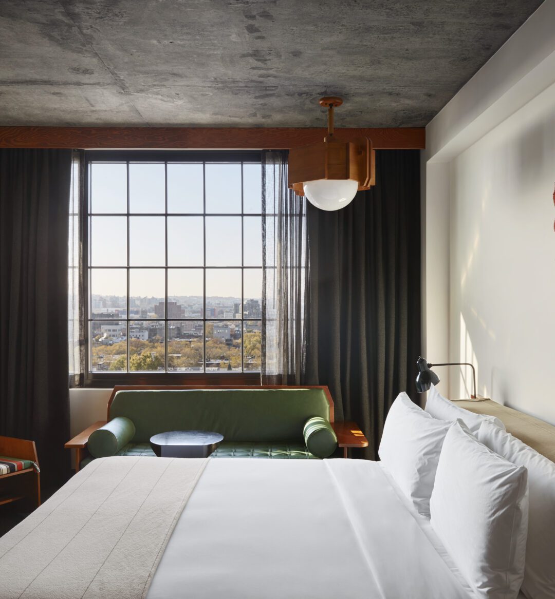 A room with green sofa, striped chair and city views featuring a park and greenery