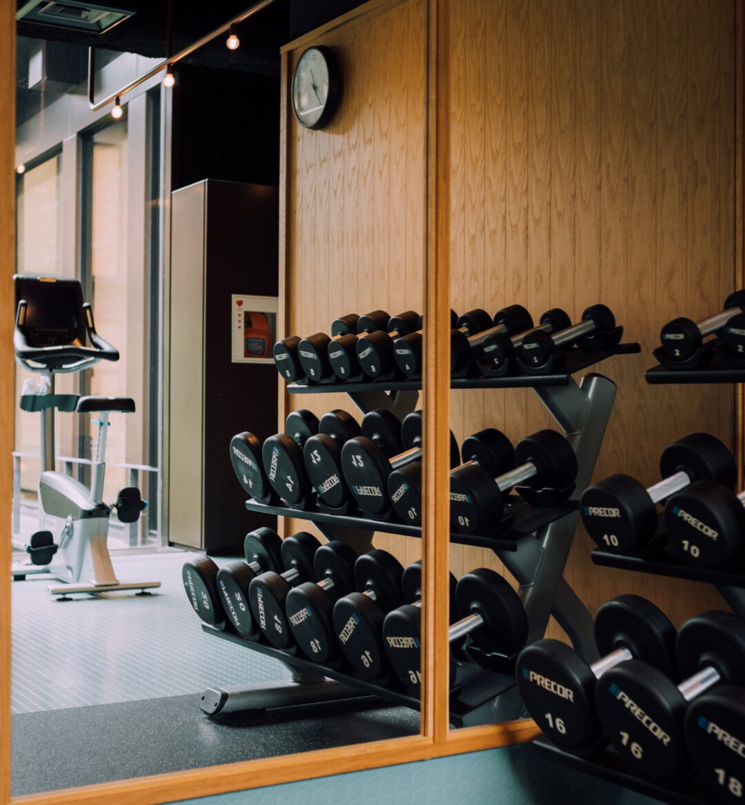 a photo of a gym with equipment that includes free weights and exercise bikes.