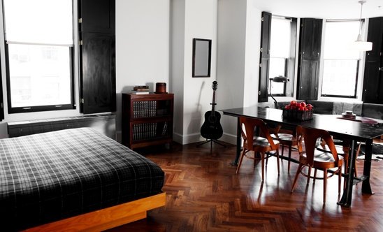 A long table with 4 chairs sits on dark mahogany polished wooden floors