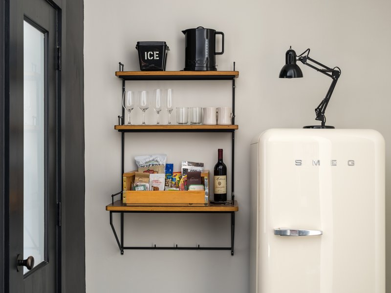 A multi level shelf features snacks, wine glasses, mugs, an icebucket, and a kettle