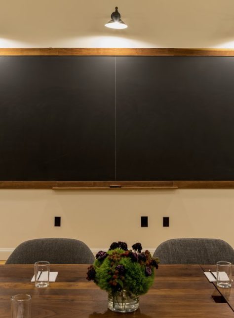 Ace Hotel New York meetings room with blackboard background and large dining table.