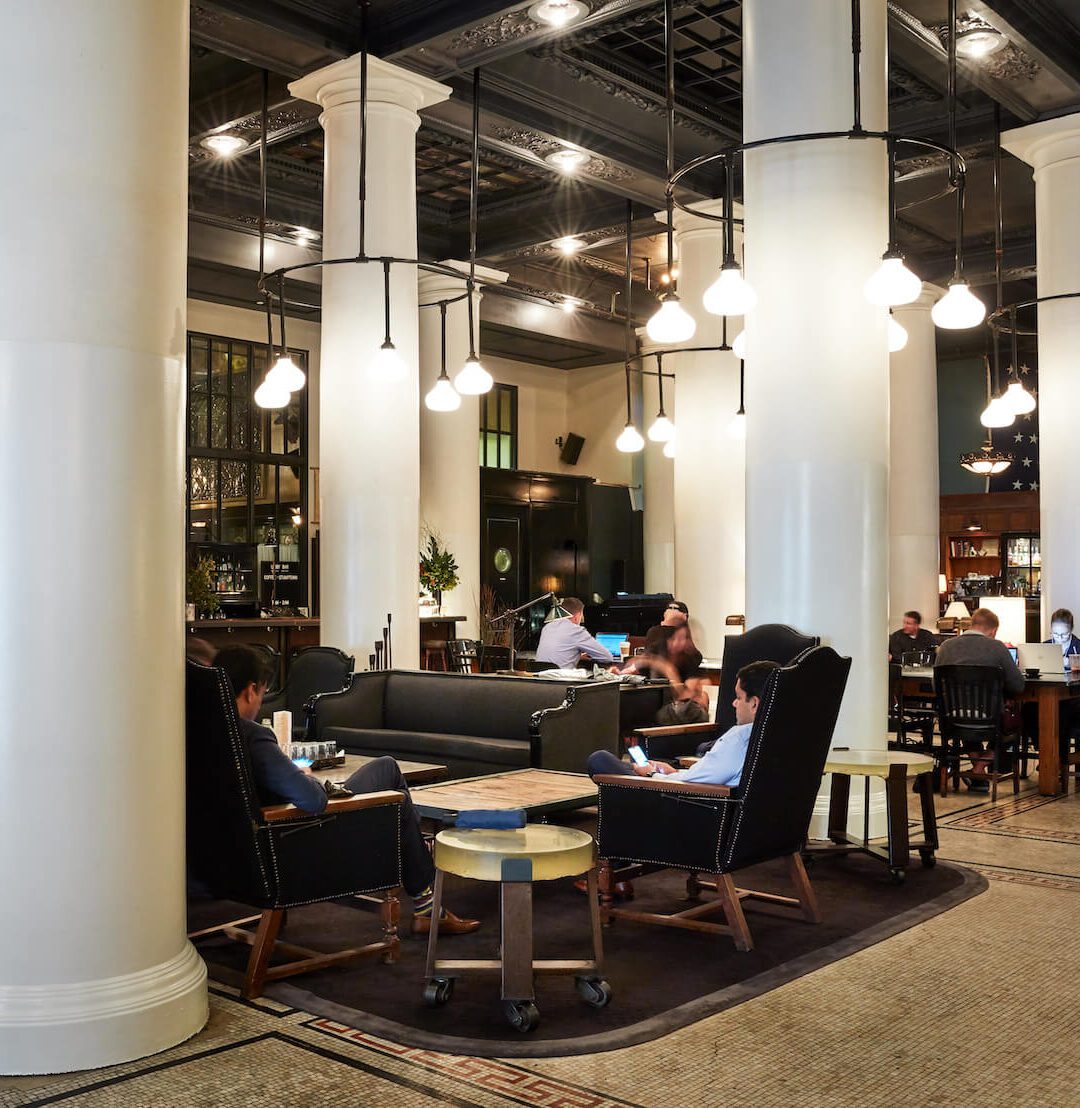 a lobby filled with seating, featuring century old mosaic tile and large pillars adorning the space