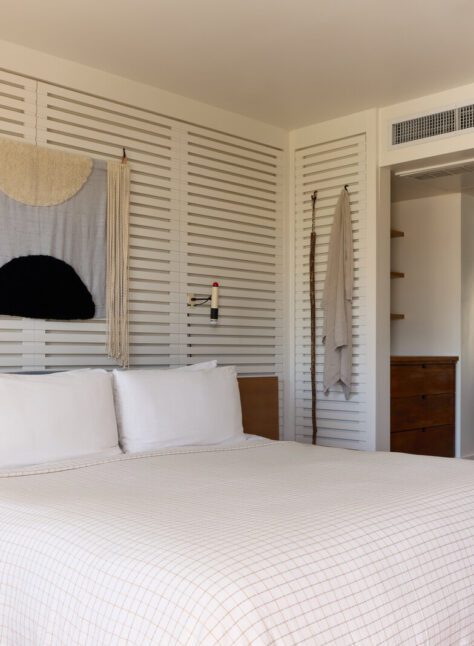 A private bedroom has robes adorning the wall and wall lamps for light into the night