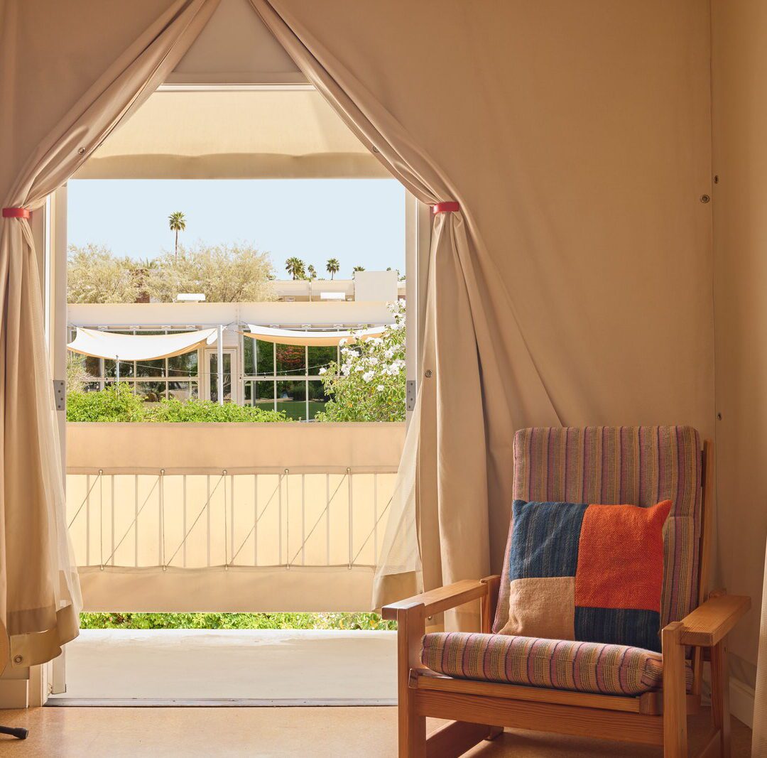 a canopy door is flanked by an acoustic guitar and chair with plaid pillow