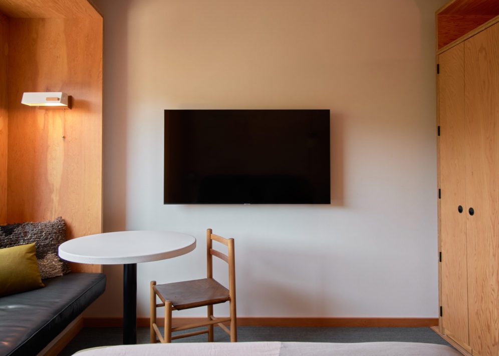 A television sits against a wall, and to its left is a standing closet for hanging clothes