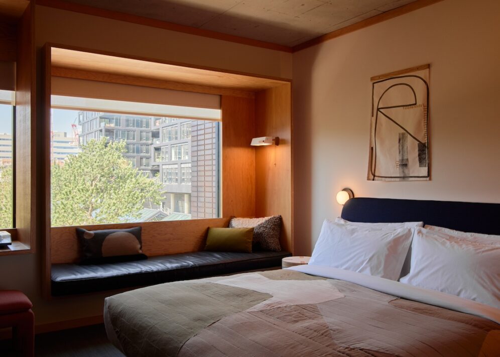 A black leather seating area is next to a bed; plush cushions provide added comfort